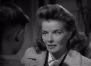 Movie still from “Woman of the Year” (1942), directed by George Stevens – A black - and - white photo of a woman in a coat; Close Up shot, Over the shoulder angle