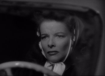 Movie still from “Woman of the Year” (1942), directed by George Stevens – A black - and - white photo of a woman in a car; Close Up shot, Over the shoulder angle