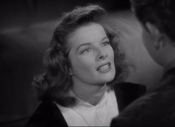 Movie still from “Woman of the Year” (1942), directed by George Stevens – A black - and - white photo of a woman in a white shirt; Close Up shot, Over the shoulder angle