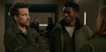 Movie still from “Another Life” (2019), created by Aaron Martin – Two men standing next to each other in front of a building; Close Up shot, Over the shoulder angle