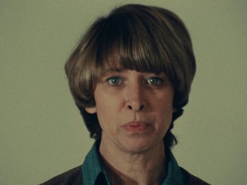 Movie still from “Women Reply” (1975), directed by Agnès Varda – A woman with a short hair cut and bangs; Close Up shot, Low angle