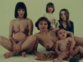 Movie still from “Women Reply” (1975), directed by Agnès Varda – A group of naked women and babies sitting on the ground; Medium shot, Overhead angle