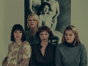 Movie still from “Women Reply” (1975), directed by Agnès Varda – A group of women standing next to each other in front of a picture; Medium shot, Overhead angle