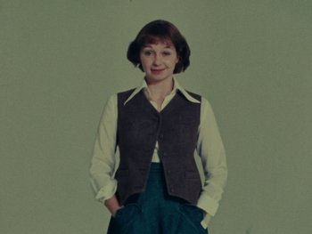 Movie still from “Women Reply” (1975), directed by Agnès Varda – A woman standing in front of a green background; Medium shot, Low angle