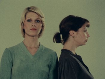 Movie still from “Women Reply” (1975), directed by Agnès Varda – Two women standing side by side in front of each other; Medium shot, Low angle
