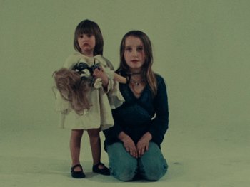 Movie still from “Women Reply” (1975), directed by Agnès Varda – A young girl and a little girl sitting on the ground; Medium shot, High angle