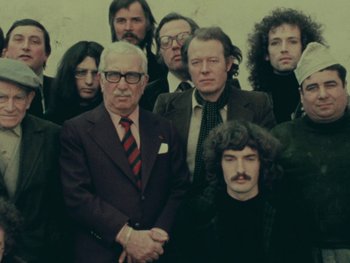 Movie still from “Women Reply” (1975), directed by Agnès Varda – A group of people standing next to each other in front of a wall; Medium shot, High angle