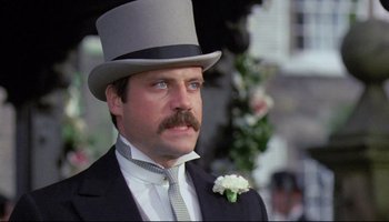 Movie still from “Women in Love” (1969), directed by Ken Russell – A person wearing a suit and a top hat; Close Up shot, Low angle