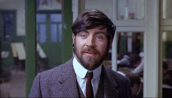 Movie still from “Women in Love” (1969), directed by Ken Russell – A man in a suit and tie with a goatee; Close Up shot, Over the shoulder angle