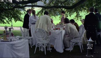 Movie still from “Women in Love” (1969), directed by Ken Russell – A group of people sitting at a table with food; Wide shot, High angle