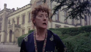 Movie still from “Women in Love” (1969), directed by Ken Russell – An older woman with curly red hair and an evil look on her face; Close Up shot, Low angle