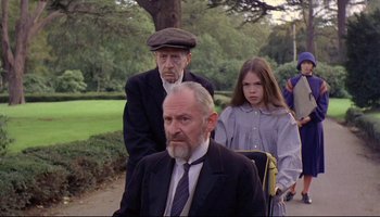 Movie still from “Women in Love” (1969), directed by Ken Russell – A man and a woman and an older man and a little girl; Medium shot, Low angle