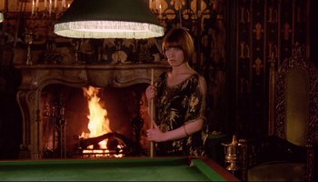 Movie still from “Women in Love” (1969), directed by Ken Russell – A woman standing in front of a pool table in front of a fireplace; Medium shot, High angle