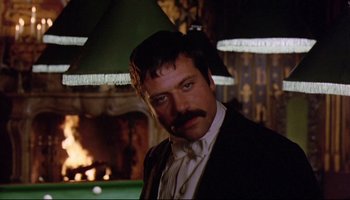 Movie still from “Women in Love” (1969), directed by Ken Russell – A man in a suit and tie standing in front of a pool table; Close Up shot, Low angle