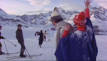 Movie still from “Women in Love” (1969), directed by Ken Russell – A group of skiers on a snowy slope with mountains in the background; Wide shot, Low angle