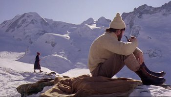 Movie still from “Women in Love” (1969), directed by Ken Russell – A man sitting on the ground in the middle of a snowy field; Wide shot, Low angle