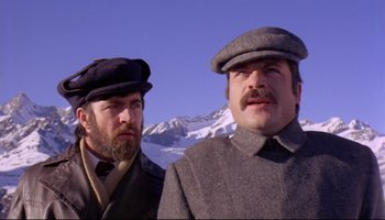 Movie still from “Women in Love” (1969), directed by Ken Russell – Two men in hats and coats standing next to each other in front of a snowy mountain; Close Up shot, Low angle