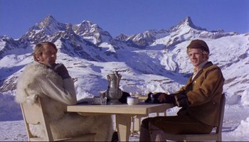 Movie still from “Women in Love” (1969), directed by Ken Russell – Two people sitting at a table in the snow; Medium shot, Low angle