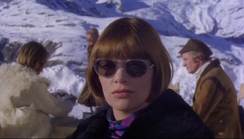 Movie still from “Women in Love” (1969), directed by Ken Russell – A woman wearing sunglasses in front of a snowy mountain; Close Up shot, Low angle