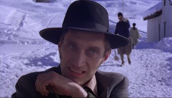 Movie still from “Women in Love” (1969), directed by Ken Russell – A man in a black hat is sitting in the snow; Close Up shot, Low angle