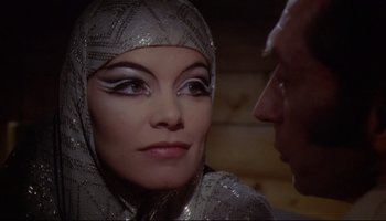 Movie still from “Women in Love” (1969), directed by Ken Russell – A woman in a silver dress looking at a man in a black suit; Close Up shot, Over the shoulder angle