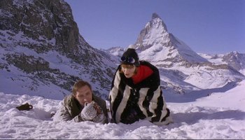 Movie still from “Women in Love” (1969), directed by Ken Russell – Two people sitting in the snow on top of a mountain; Wide shot, High angle