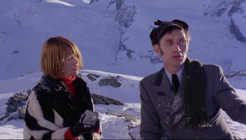 Movie still from “Women in Love” (1969), directed by Ken Russell – A man and a woman standing in the snow; Medium shot, Low angle
