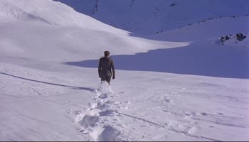 Movie still from “Women in Love” (1969), directed by Ken Russell – A man is walking through the snow on a mountain; Extreme Wide shot, High angle