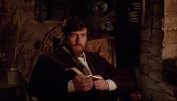 Movie still from “Women in Love” (1969), directed by Ken Russell – A man holding a banana in his hands; Medium shot, Low angle