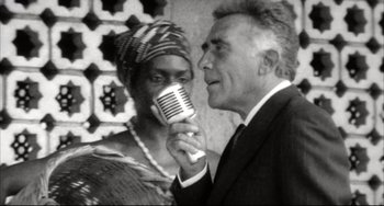 Movie still from “Women on the Verge of a Nervous Breakdown” (1988), directed by Pedro Almodóvar – An older man holding a microphone next to an older woman; Close Up shot, Over the shoulder angle