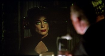 Movie still from “Women on the Verge of a Nervous Breakdown” (1988), directed by Pedro Almodóvar – A woman with green eye shadow is looking at a man with a glass of wine; Close Up shot, Over the shoulder angle