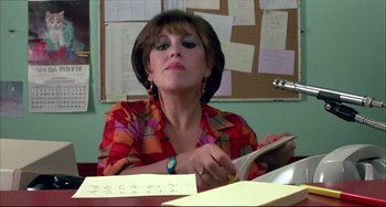 Movie still from “Women on the Verge of a Nervous Breakdown” (1988), directed by Pedro Almodóvar – A woman sitting at a table with a book in her hand; Close Up shot, Over the shoulder angle