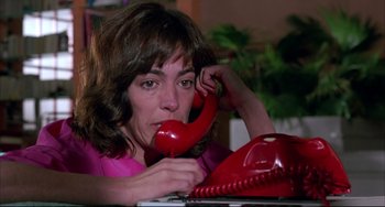 Movie still from “Women on the Verge of a Nervous Breakdown” (1988), directed by Pedro Almodóvar – A woman sitting at a table holding a red phone up to her ear; Close Up shot, High angle