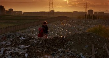 Movie still from “Women on the Verge of a Nervous Breakdown” (1988), directed by Pedro Almodóvar – A child is standing in a pile of trash at sunset; Extreme Wide shot, Low angle