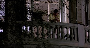 Movie still from “Women on the Verge of a Nervous Breakdown” (1988), directed by Pedro Almodóvar – A man standing on a balcony looking out the window; Wide shot, Low angle