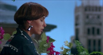 Movie still from “Women on the Verge of a Nervous Breakdown” (1988), directed by Pedro Almodóvar – A person with flowers near a building; Close Up shot, Low angle