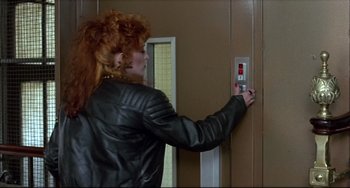 Movie still from “Women on the Verge of a Nervous Breakdown” (1988), directed by Pedro Almodóvar – A woman in a leather jacket is pressing a button on a door; Medium shot, Low angle