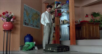 Movie still from “Women on the Verge of a Nervous Breakdown” (1988), directed by Pedro Almodóvar – A man standing next to a suitcase in a room; Wide shot, Low angle