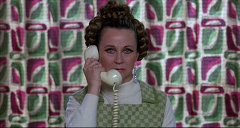 Movie still from “Women on the Verge of a Nervous Breakdown” (1988), directed by Pedro Almodóvar – A woman in a checkered apron holding a phone to her ear; Close Up shot, High angle