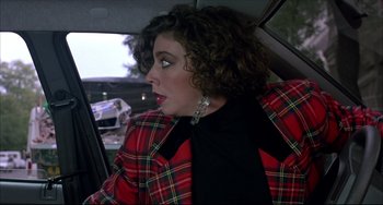 Movie still from “Women on the Verge of a Nervous Breakdown” (1988), directed by Pedro Almodóvar – A woman sitting in the back seat of a car wearing a plaid jacket; Close Up shot, Over the shoulder angle
