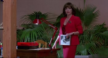 Movie still from “Women on the Verge of a Nervous Breakdown” (1988), directed by Pedro Almodóvar – A woman in a red suit holding a box; Medium shot, Over the shoulder angle