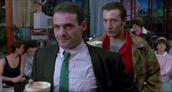 Movie still from “Women on the Verge of a Nervous Breakdown” (1988), directed by Pedro Almodóvar – A man in a suit and tie next to another man in a red jacket; Medium shot, Low angle
