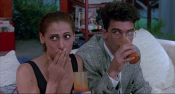 Movie still from “Women on the Verge of a Nervous Breakdown” (1988), directed by Pedro Almodóvar – A man and a woman sitting next to each other at a table; Medium shot, Over the shoulder angle