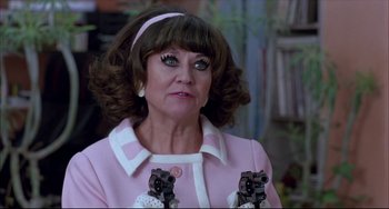 Movie still from “Women on the Verge of a Nervous Breakdown” (1988), directed by Pedro Almodóvar – A woman in a pink coat and a white headband; Close Up shot, Over the shoulder angle