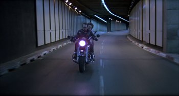 Movie still from “Women on the Verge of a Nervous Breakdown” (1988), directed by Pedro Almodóvar – Two people riding a motorcycle down a tunnel; Wide shot, Low angle