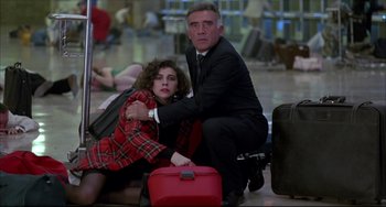 Movie still from “Women on the Verge of a Nervous Breakdown” (1988), directed by Pedro Almodóvar – A man kneeling down next to a woman in front of luggage; Wide shot, High angle