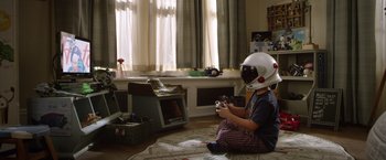 Movie still from “Wonder” (2017), directed by Stephen Chbosky – A boy wearing a helmet playing a video game; Wide shot, High angle