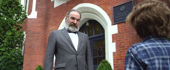 Movie still from “Wonder” (2017), directed by Stephen Chbosky – An older man in a suit stands in front of a building; Close Up shot, Low angle