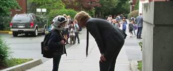 Movie still from “Wonder” (2017), directed by Stephen Chbosky – A man in a suit and a motorcycle helmet talks to another man in a suit and a motorcycle helmet; Medium shot, Over the shoulder angle