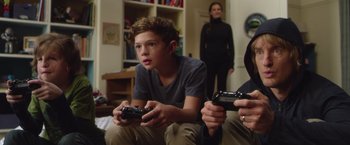 Movie still from “Wonder” (2017), directed by Stephen Chbosky – A young boy sitting on the ground holding a video game controller; Close Up shot, Over the shoulder angle